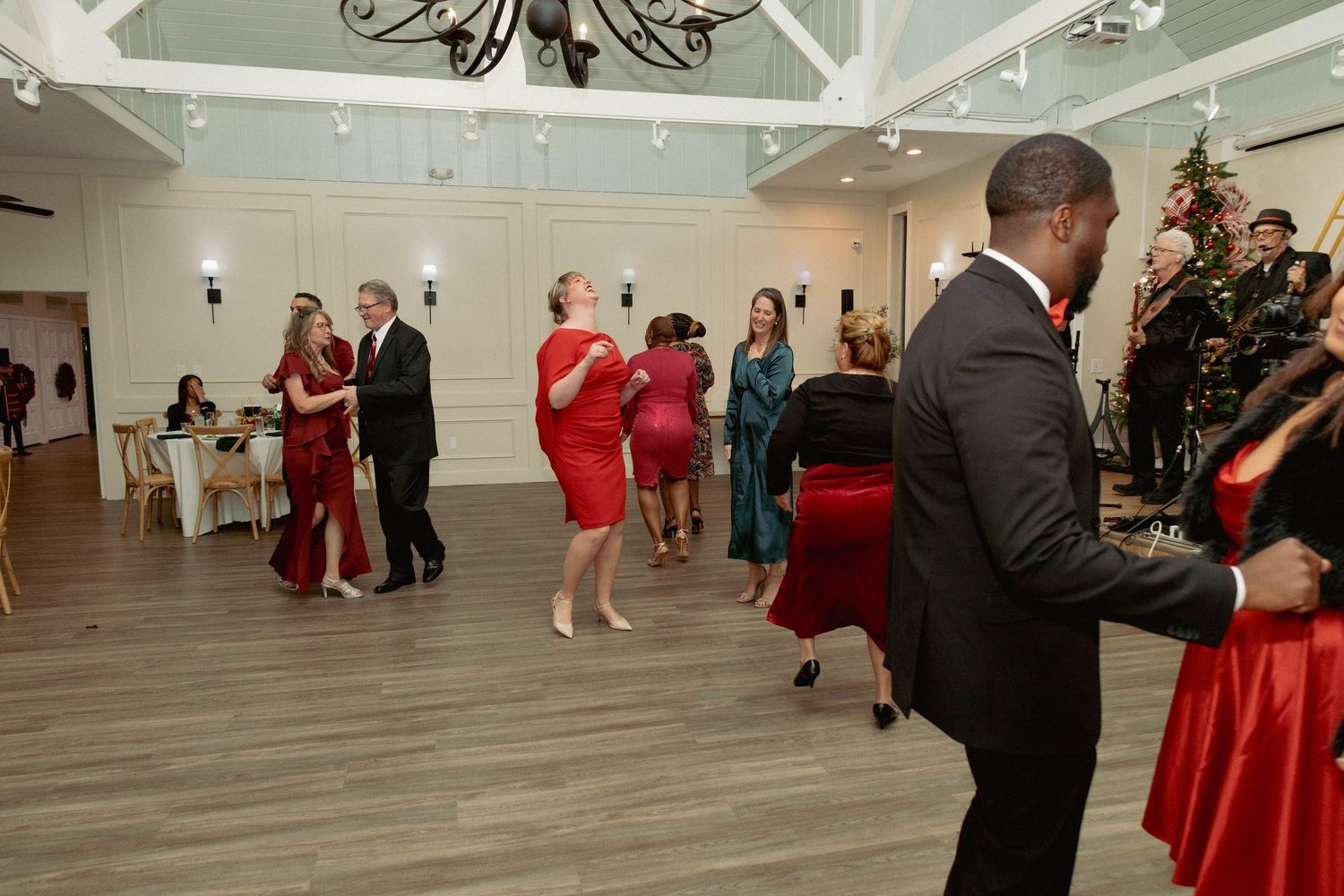 Guests dancing and socializing on a dance floor at a festive holiday party with Christmas decor.