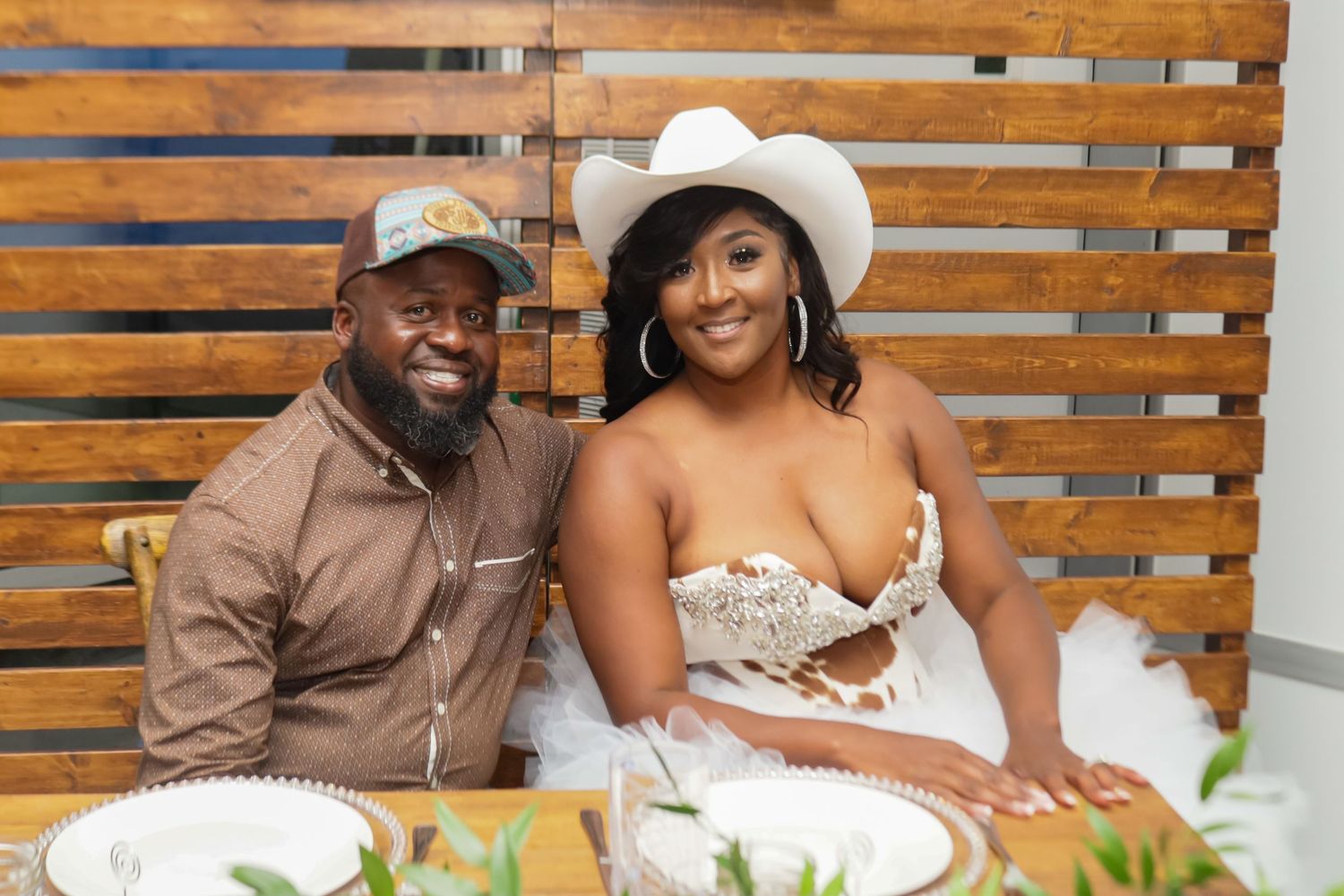 Couple smiling together at a table during a western-themed celebration event.