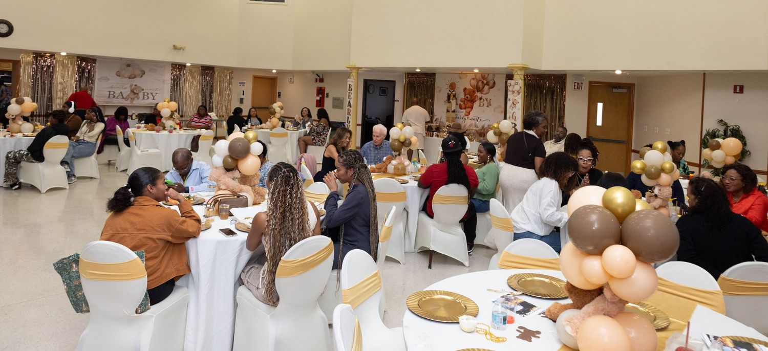 Guests seated at decorated tables during a elegant baby shower or celebration event in a banquet hall.