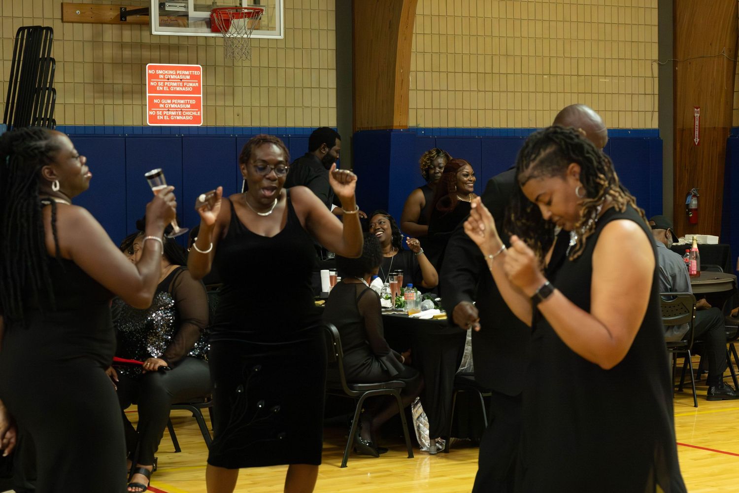 Guests in black attire dance and celebrate at a lively indoor party event.