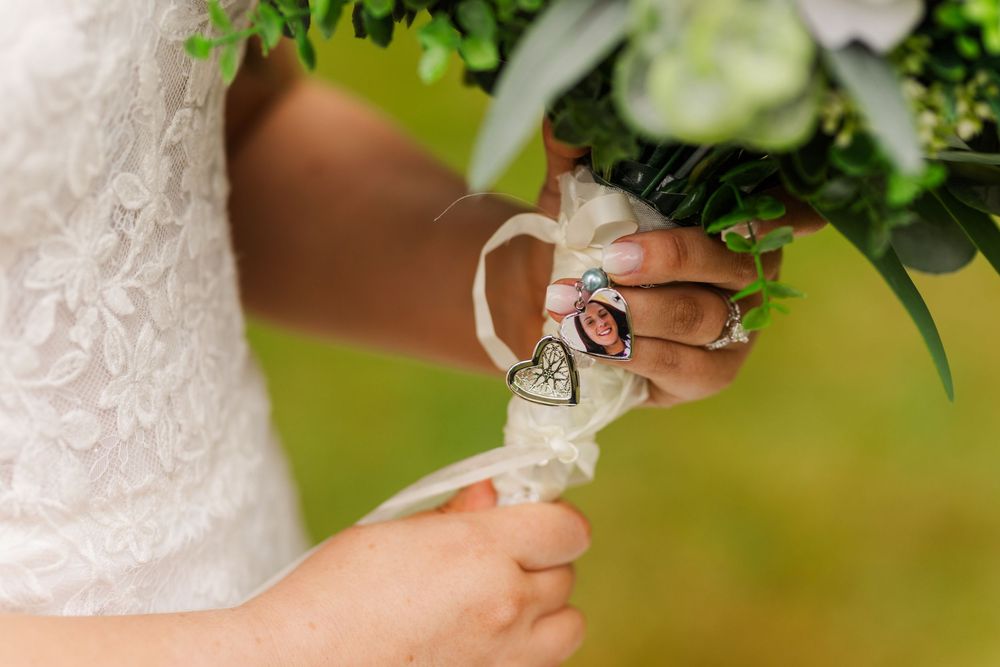 Wedding details showing hands adjusting a boutonniere with fresh white flowers and greenery against formal attire.