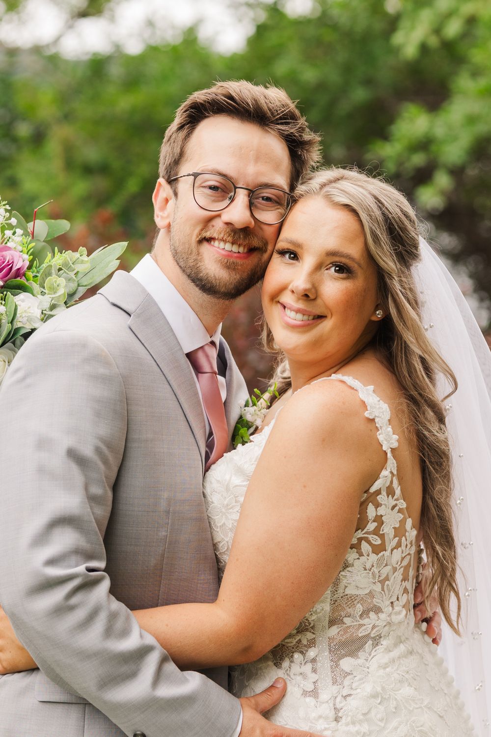 A newlywed couple shares joyful embraces and smiles in a romantic outdoor garden setting.