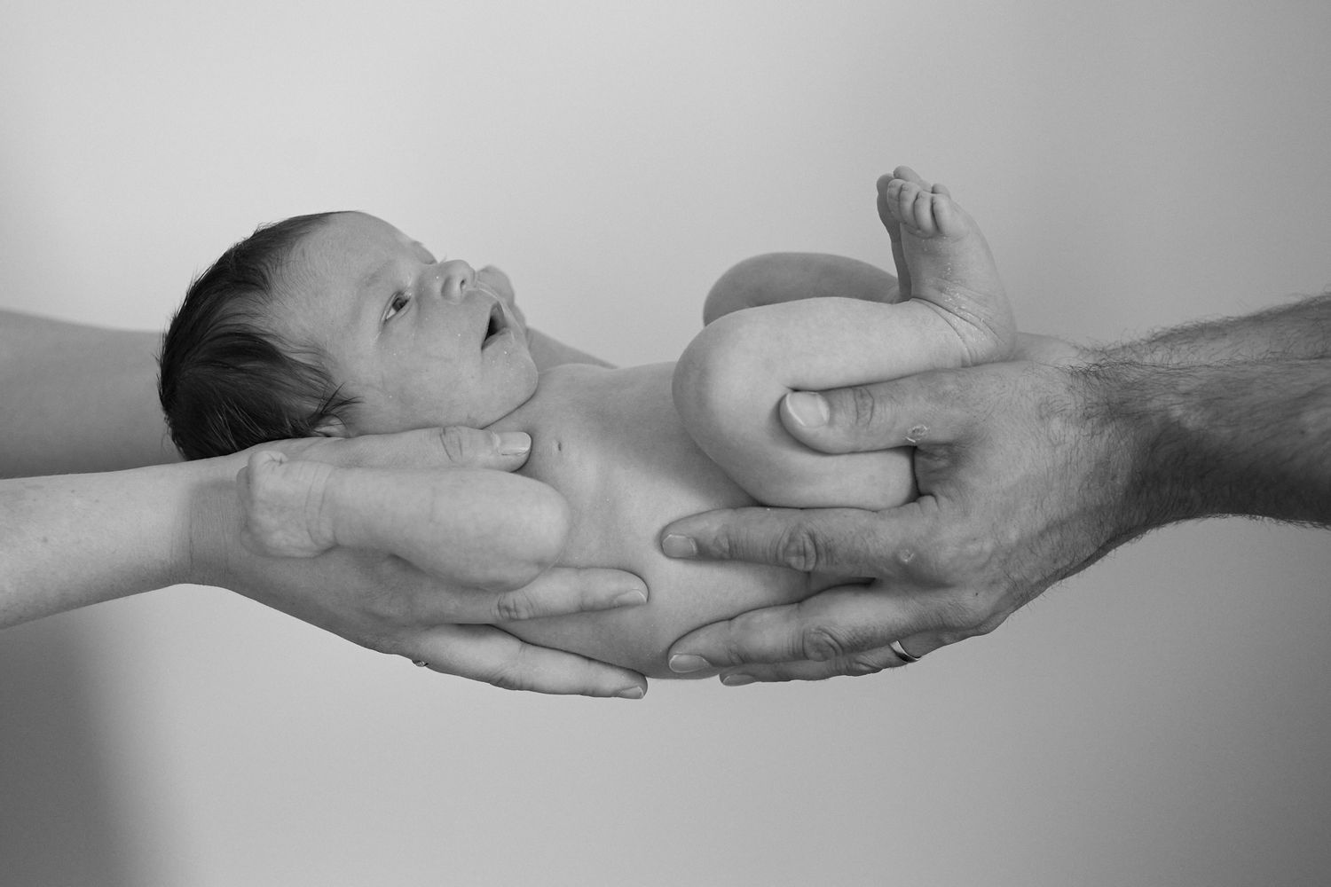 Newborn baby zwart-wit foto ligt tussen de handen van de ouders