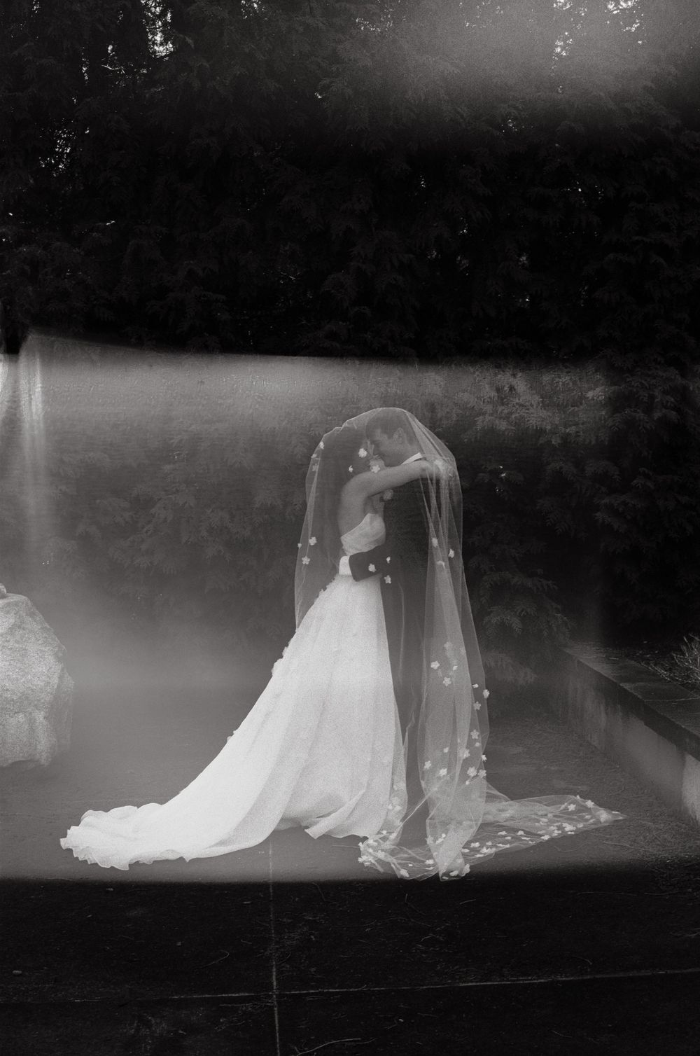 A vintage black and white photograph of a bride in an elegant wedding gown with a flowing veil.