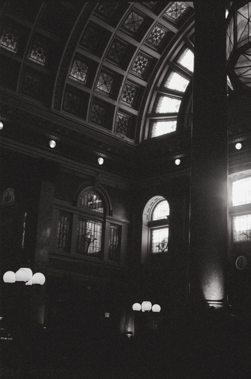 Interior of a grand historic building with arched ceiling and vintage light fixtures.
