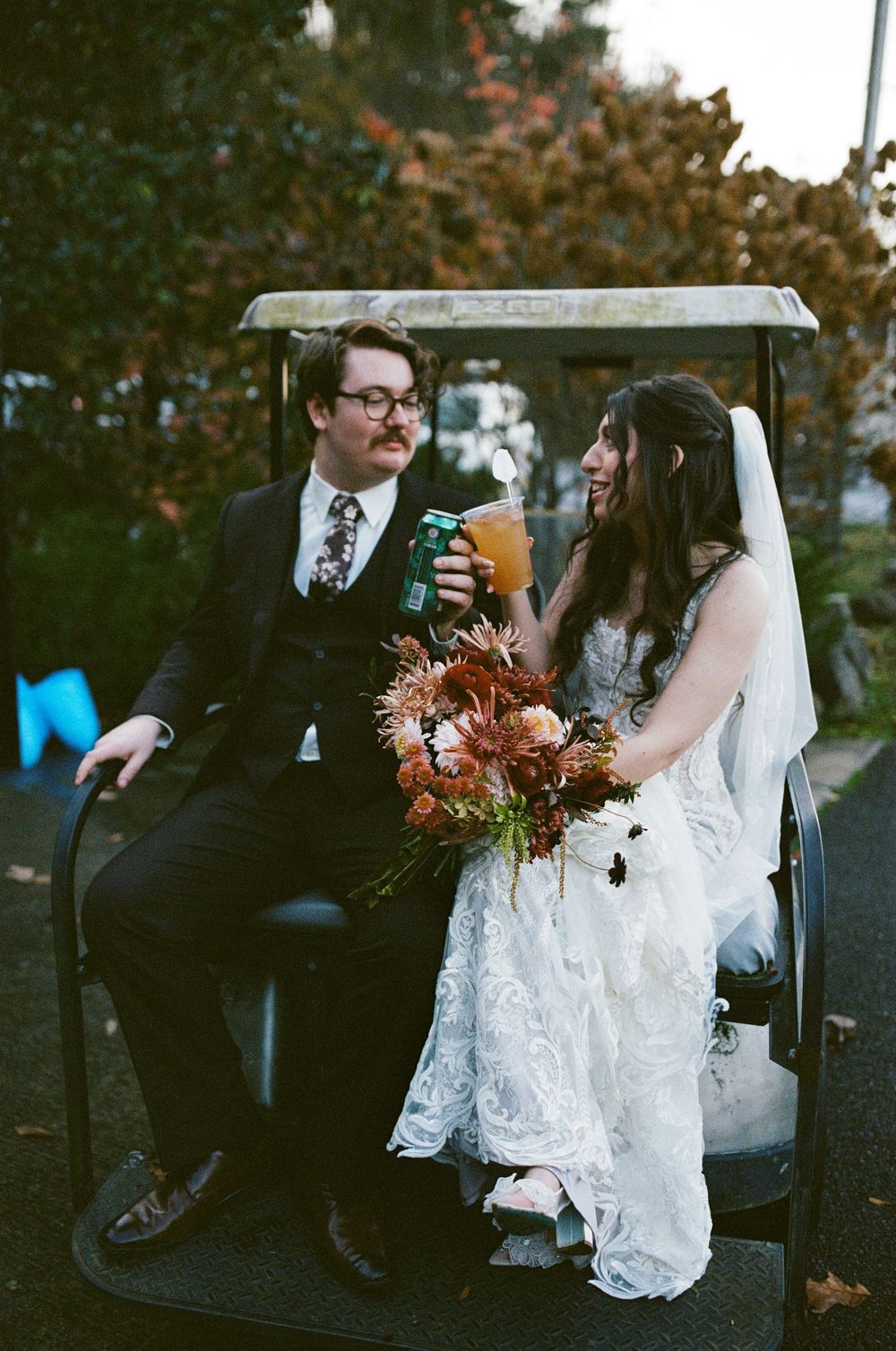 Wedding couple sitting in a vintage car during an autumn celebration.