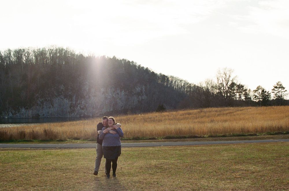 Panoramic sunset view of couple walking through golden field.