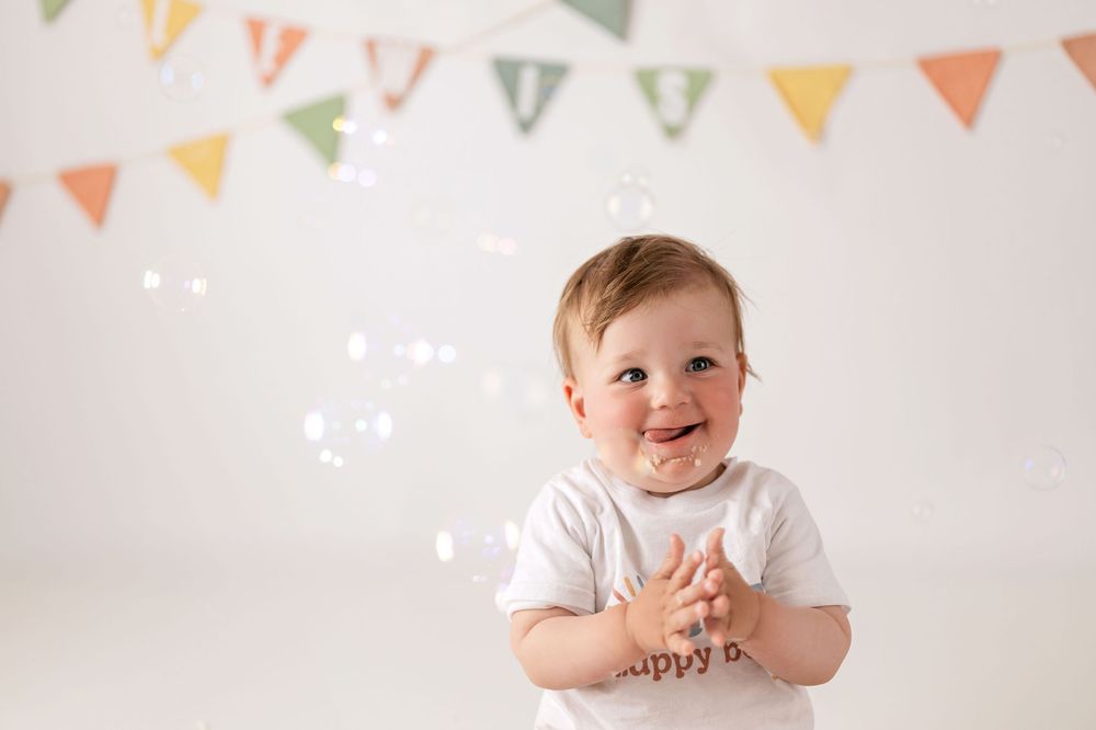 A colorful banner of triangular flags hangs above a series of smiling expressions against a white background.