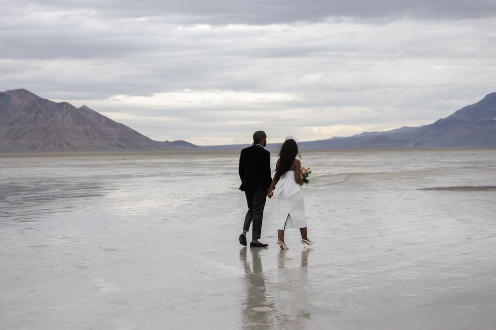 couple standing amid salt flats in a wedding attire ready for their first dance