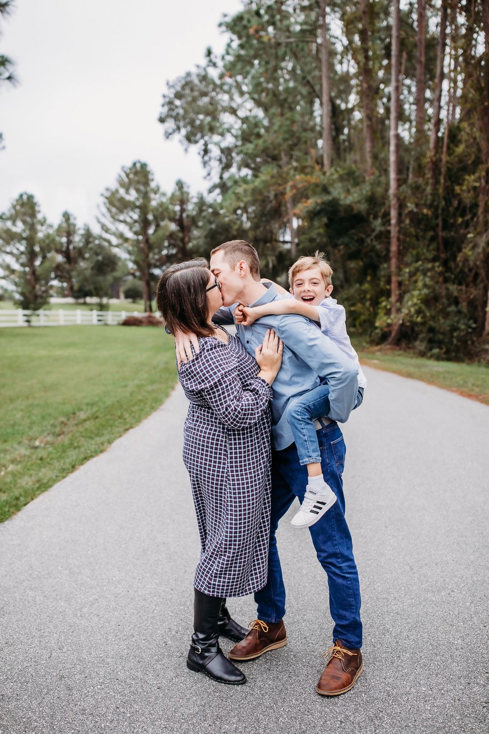 Family sharing playful moments together on a path through a pine forest on a sunny day.