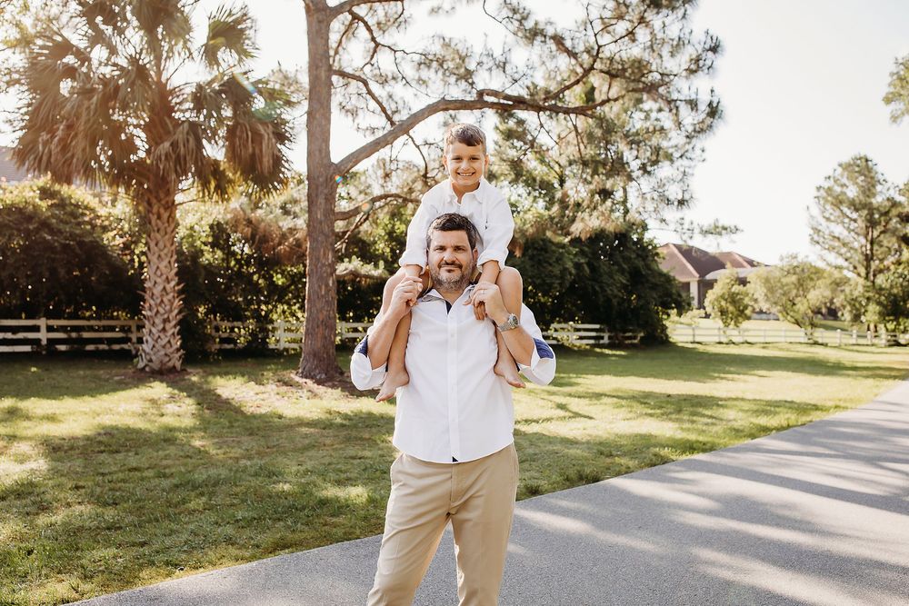 A family walks together on a tree-lined path during a golden sunset photo session.