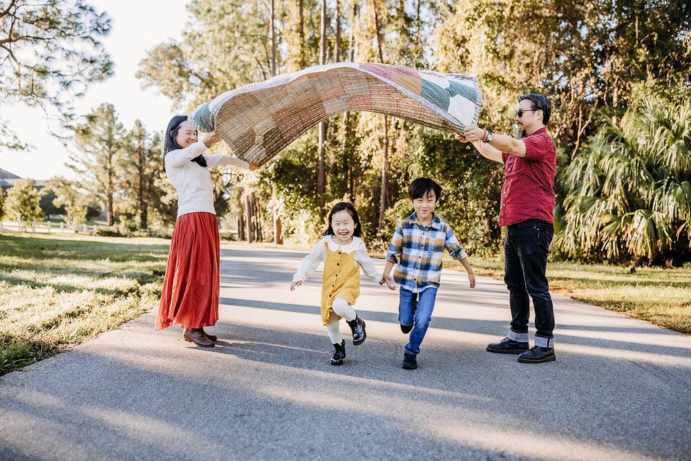 Children running and playing together on a winding park path surrounded by trees.