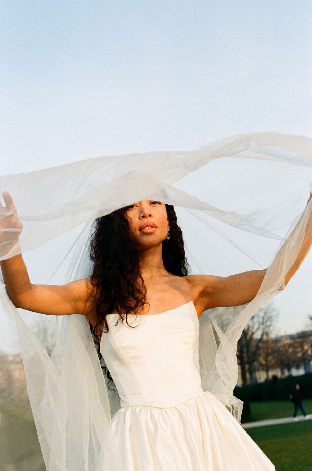 Artistic sequence of a white wedding veil flowing in the breeze against a blue sky.