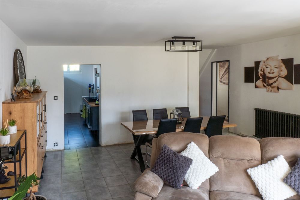 Contemporary living and dining area with beige sofa, wooden dining table and black chairs.