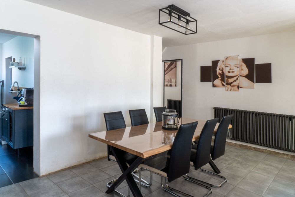 Open concept dining space with wooden table, black chairs and modern ceiling light fixture.