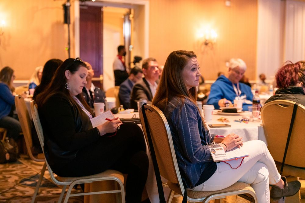 People seated at tables in a formal dining room during a conference or meeting event.