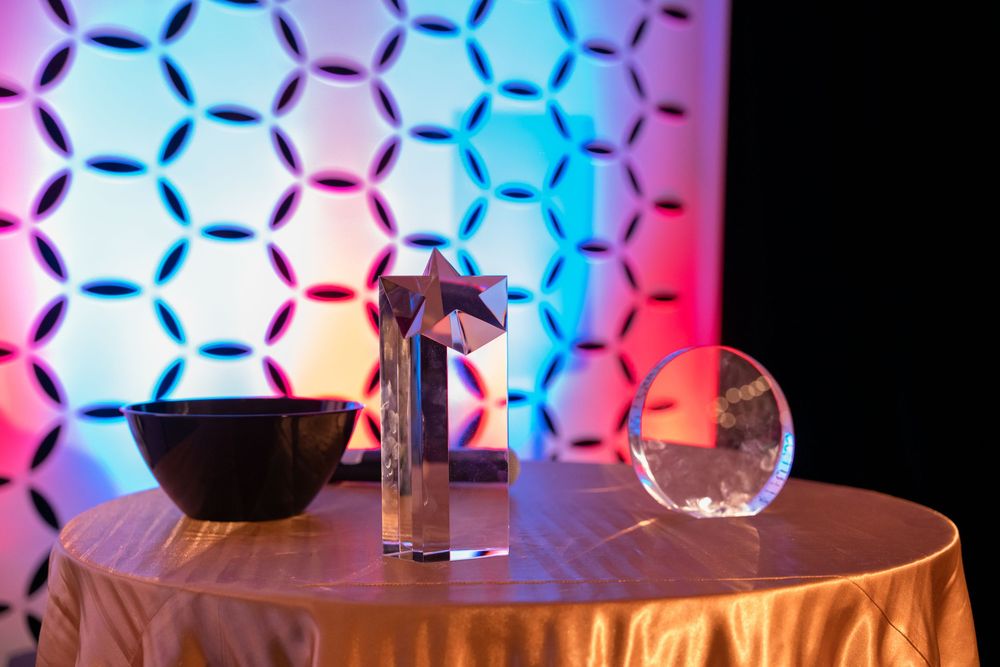 Microphone and clear orb on table with colorful honeycomb pattern lighting backdrop.