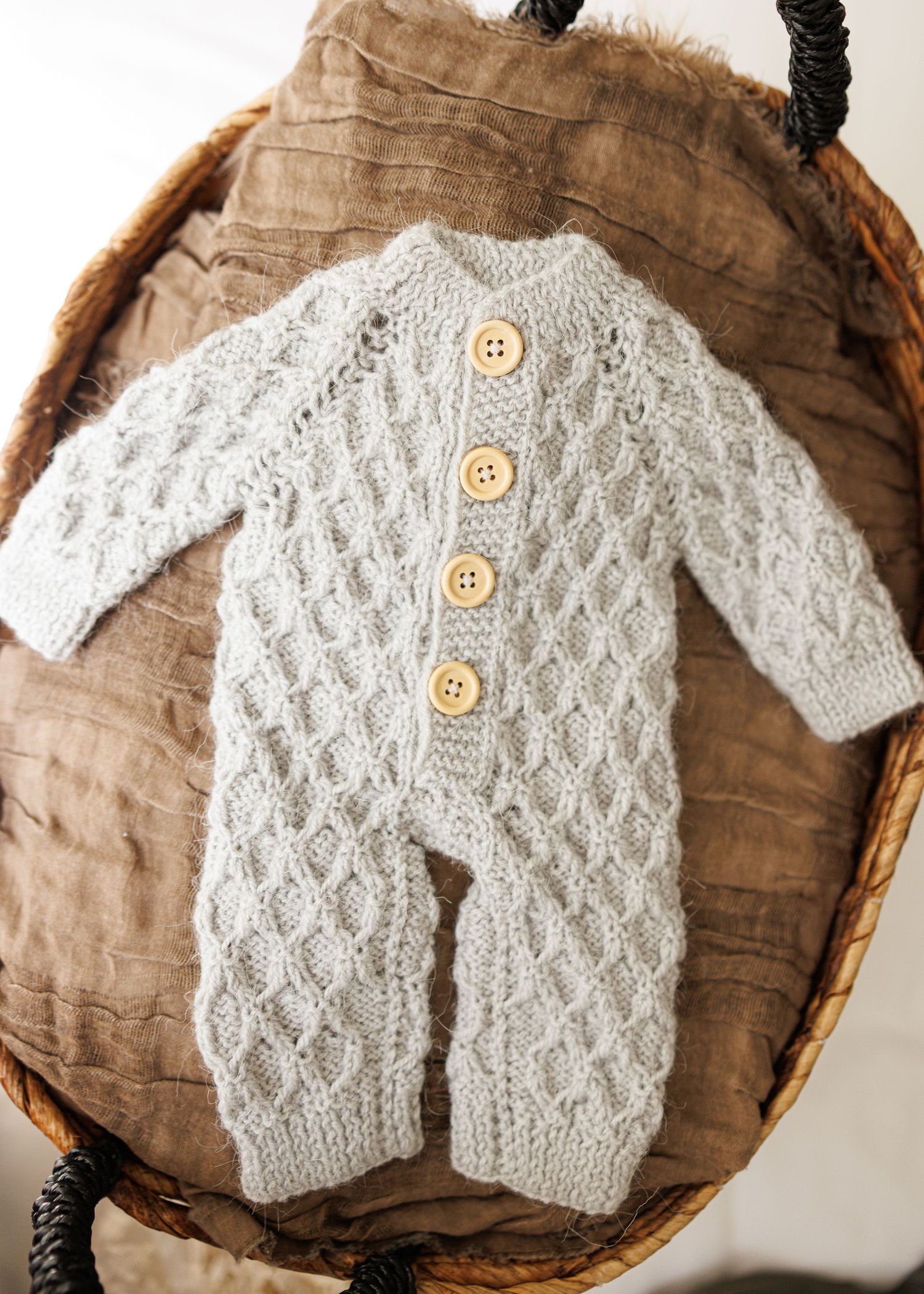 Rustic brown linen baby romper with delicate white lace trim and crochet details displayed on vintage lace background.