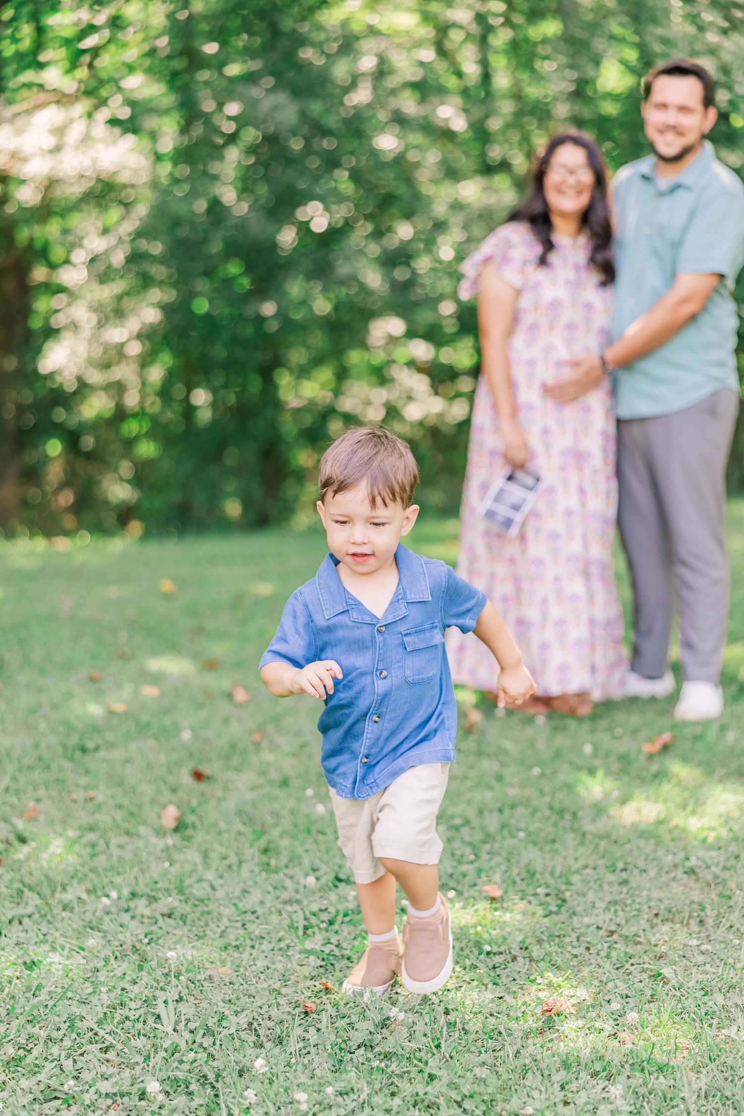Four linked photos showing a small child in a blue shirt playing and running on green grass with parents in background.
