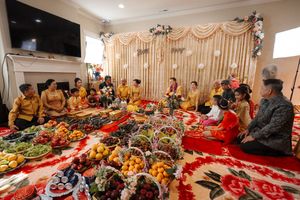 Traditional wedding ceremony gathering with abundant food spread on red tablecloths and elegant backdrop decorations.