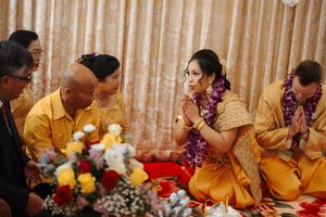 A group wearing traditional Indian attire participates in a cultural ceremony with decorative elements and flowers.