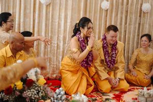 Wedding guests in vibrant yellow traditional attire and flower garlands participate in a cultural ceremony.