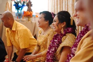 Wedding party members in yellow attire and purple leis sit together during a traditional Hawaiian ceremony.