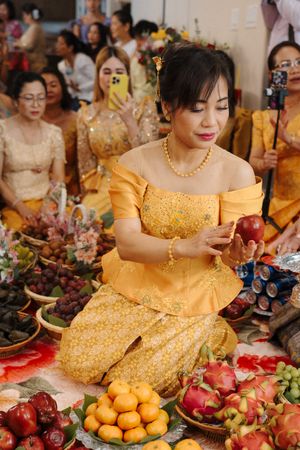 Four detailed photos showing a traditional Asian celebration with yellow dresses and abundant fresh fruits on display.