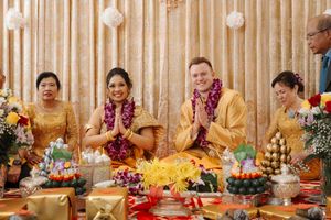 Friends gather around a colorfully decorated table with flower arrangements for a festive celebration.