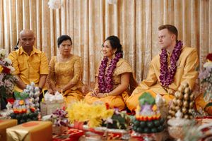A group enjoying a vibrant celebration with traditional leis and yellow attire around a decorated dining table.