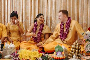 Buddhist monks in saffron robes sit in a row during a traditional ceremony with floral decorations.