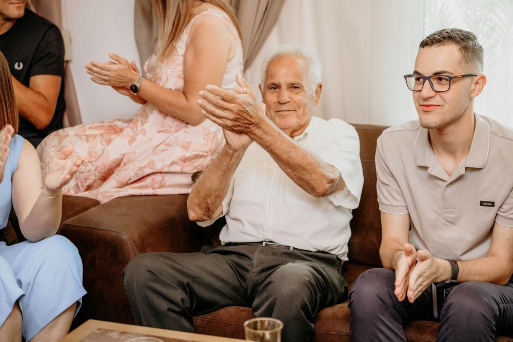 Group of elderly patients in a care home clapping and participating in a group activity or therapy session.