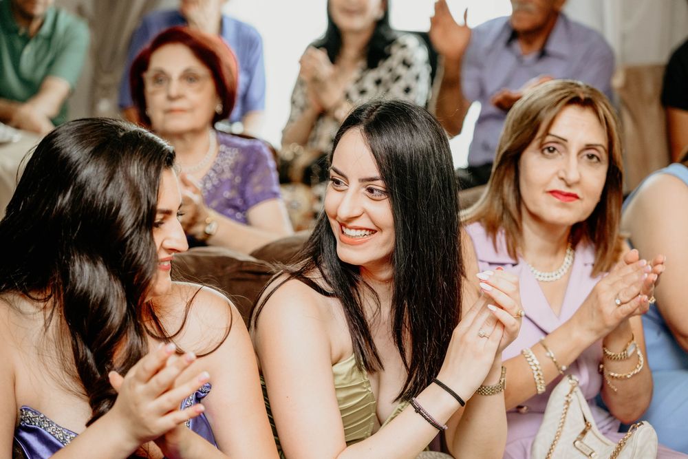 Group of wedding guests smile and laugh together during a reception celebration.