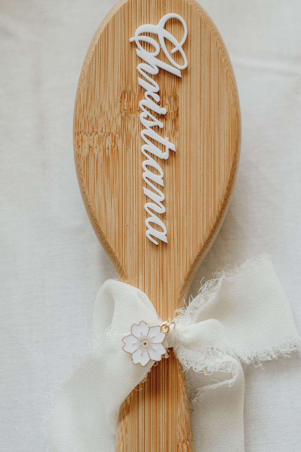 Five wooden cooking spoons decorated with white lace bows and floral details create an elegant kitchen display.