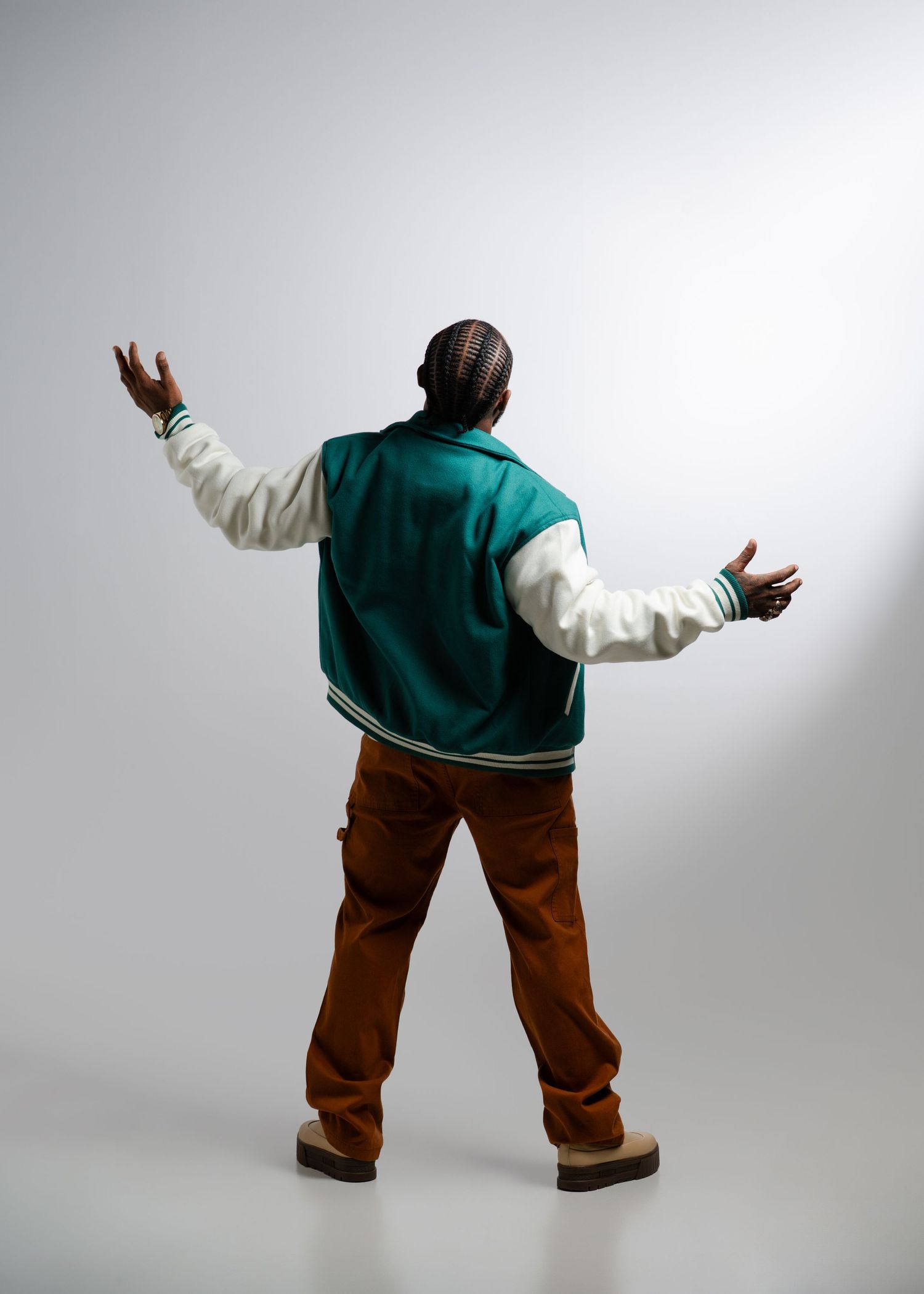 Person in teal shirt and brown pants performs dynamic dance moves in sequence against white background.