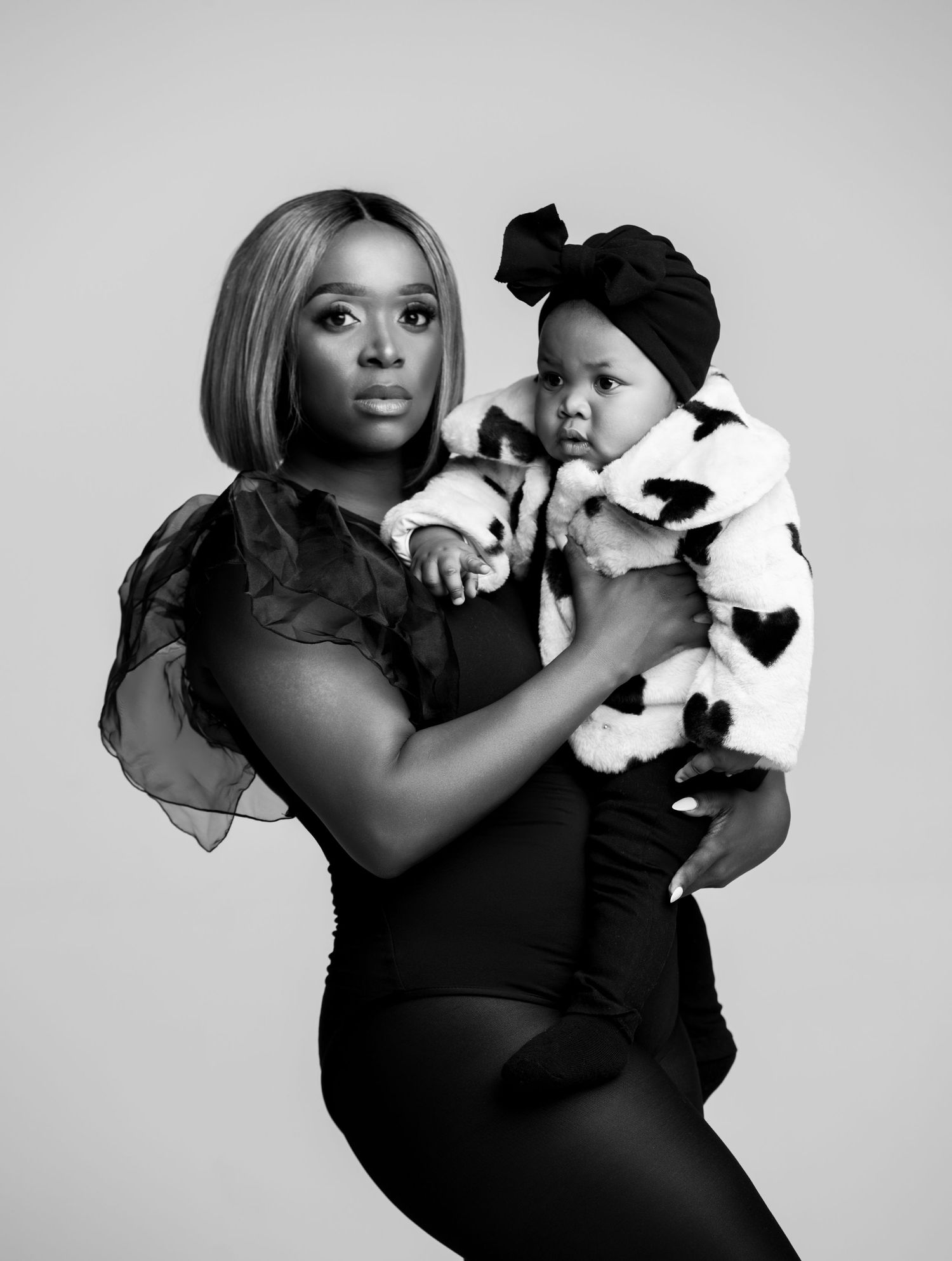 Black and white artistic maternity photo series showing a woman in black dress holding a plush toy in different poses.