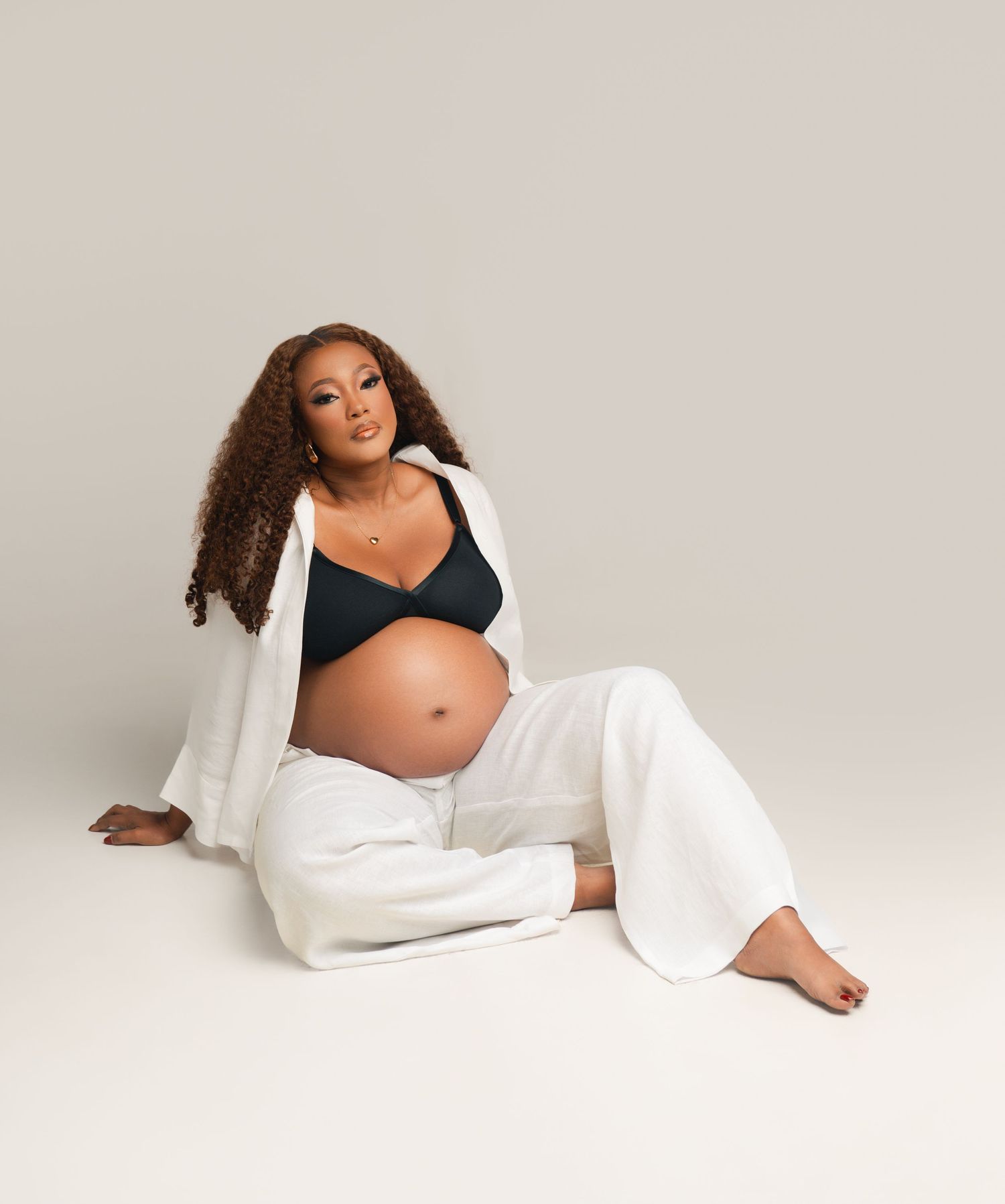 A maternity photoshoot series showing poses in white fabric against a light backdrop.