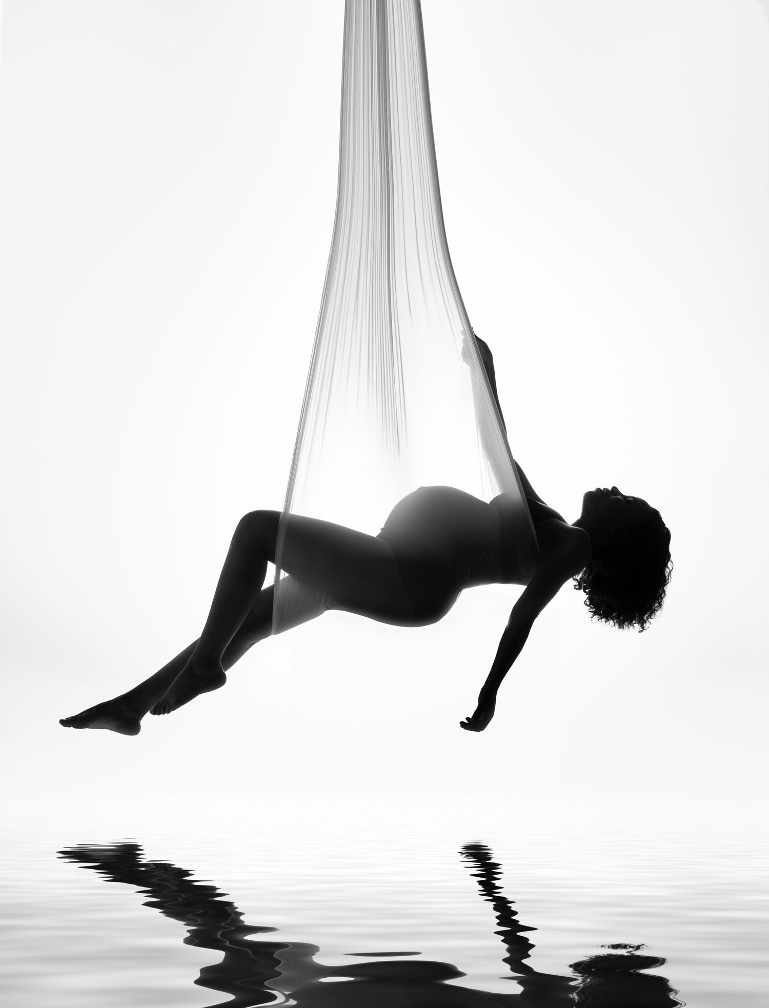 A series of minimalist black and white photos showing graceful aerial silks performers reflected in water.