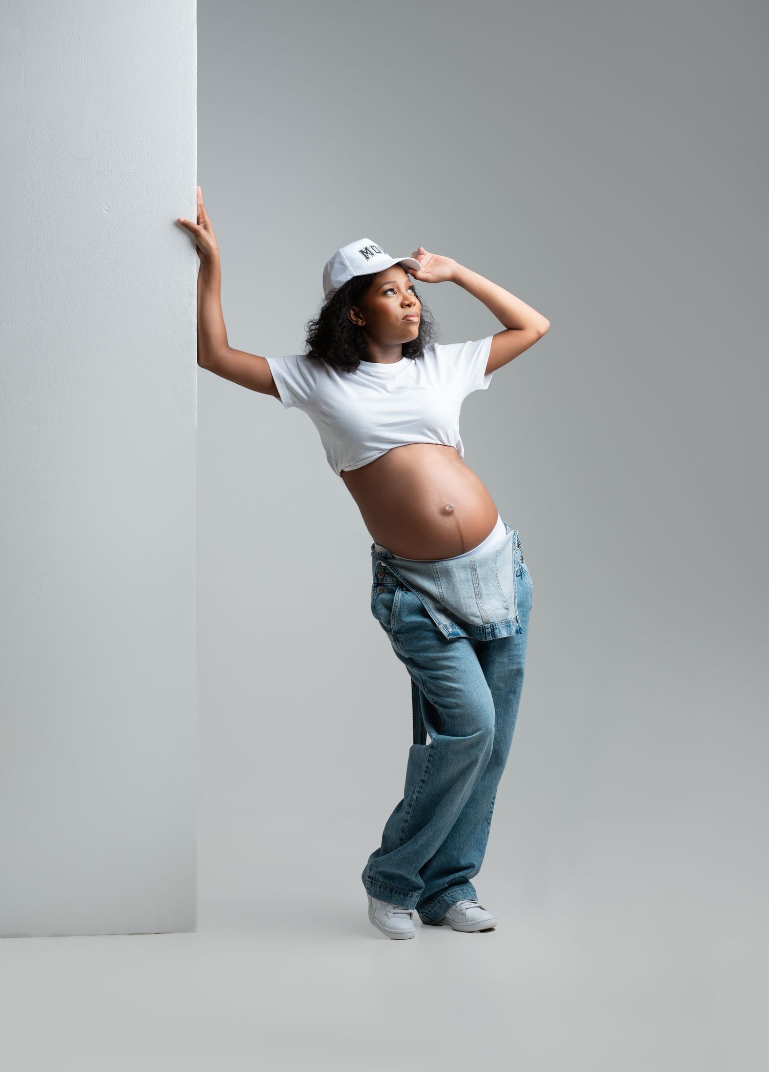 Person in jeans and white t-shirt performs dynamic dance moves against a gray studio backdrop.