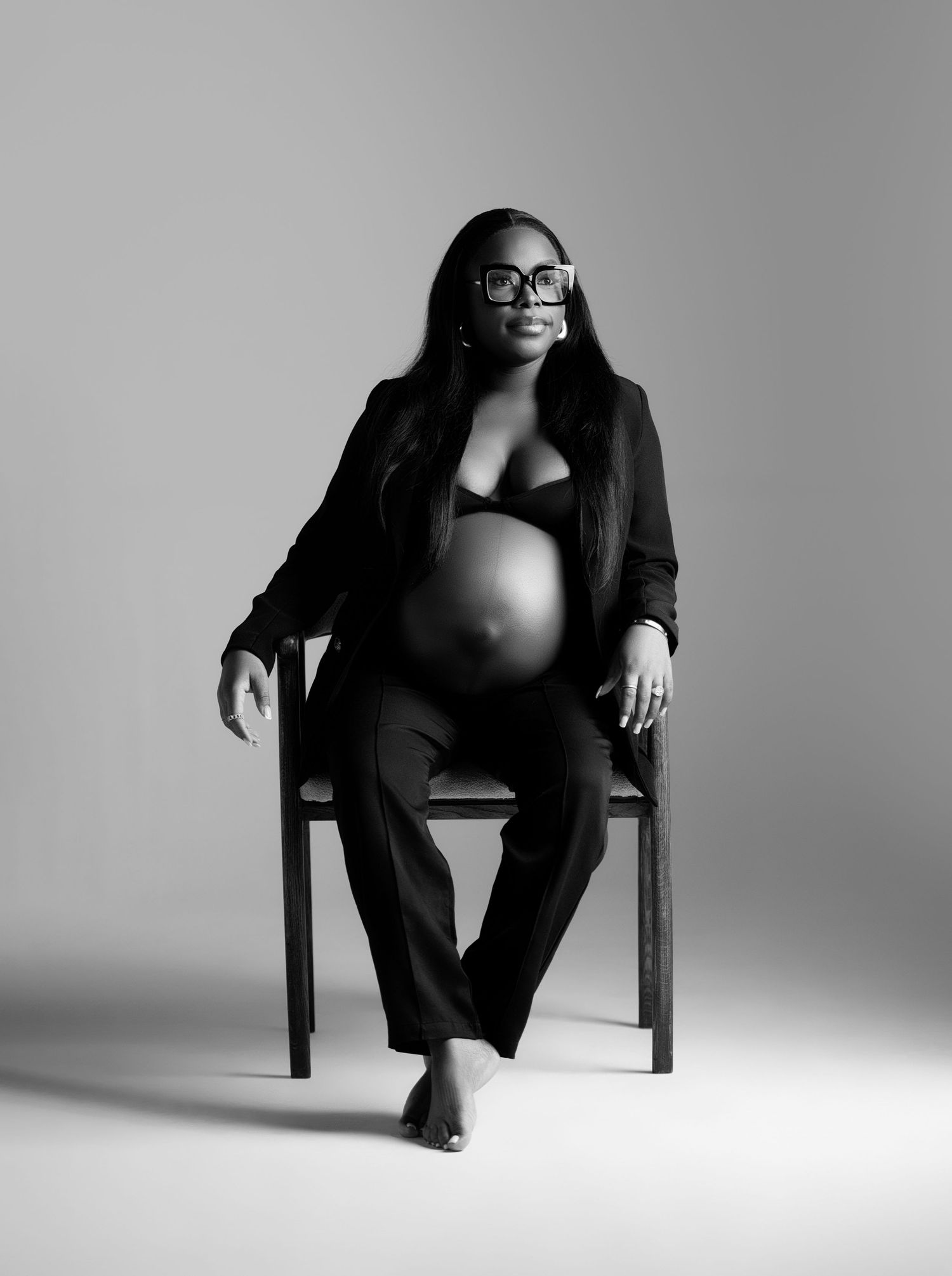 Monochromatic fashion portraits featuring elegant poses in business attire on a simple chair against white backdrop.