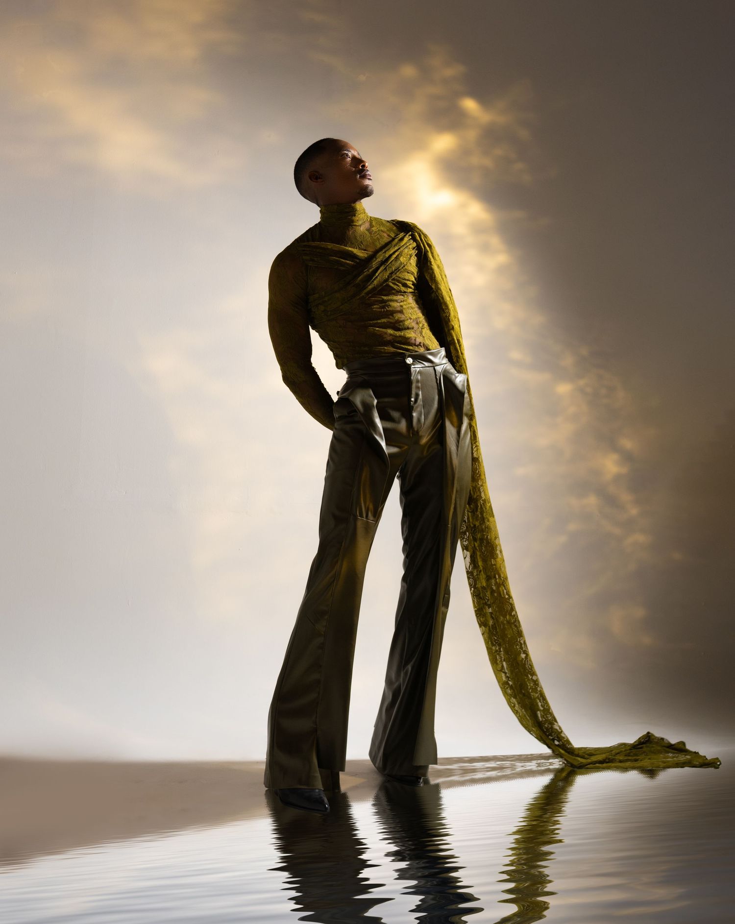 Silhouetted figure stands in reflective water against dramatic sunset sky creating mirror-like symmetry.