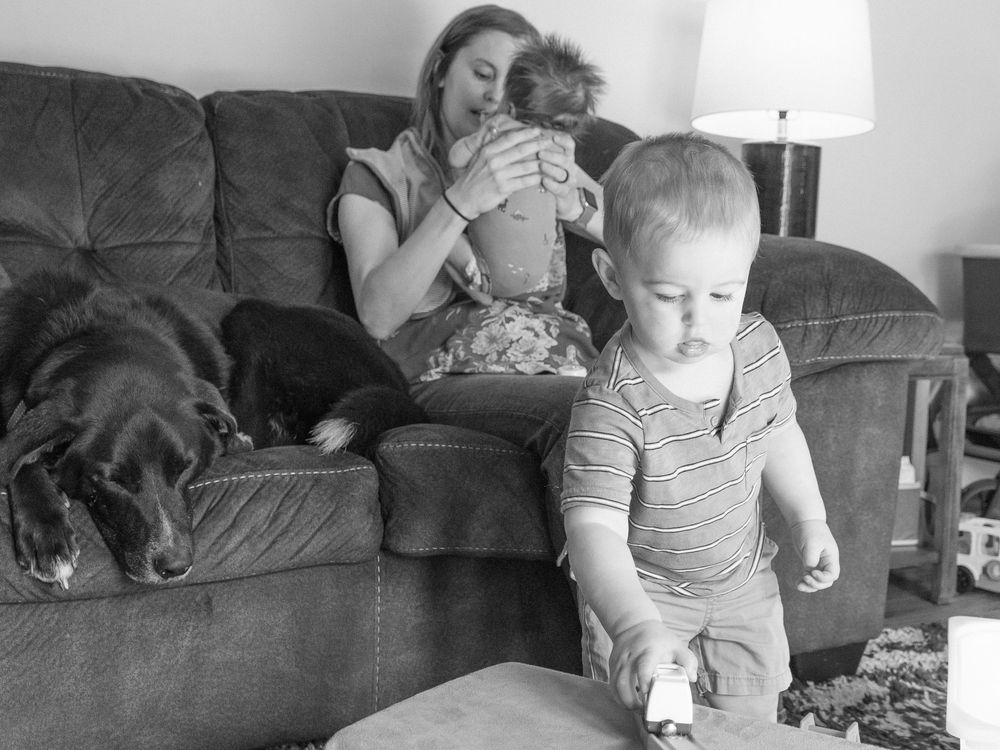 A tender black and white photo series captures a parent comforting a child in while another plays in the foreground.