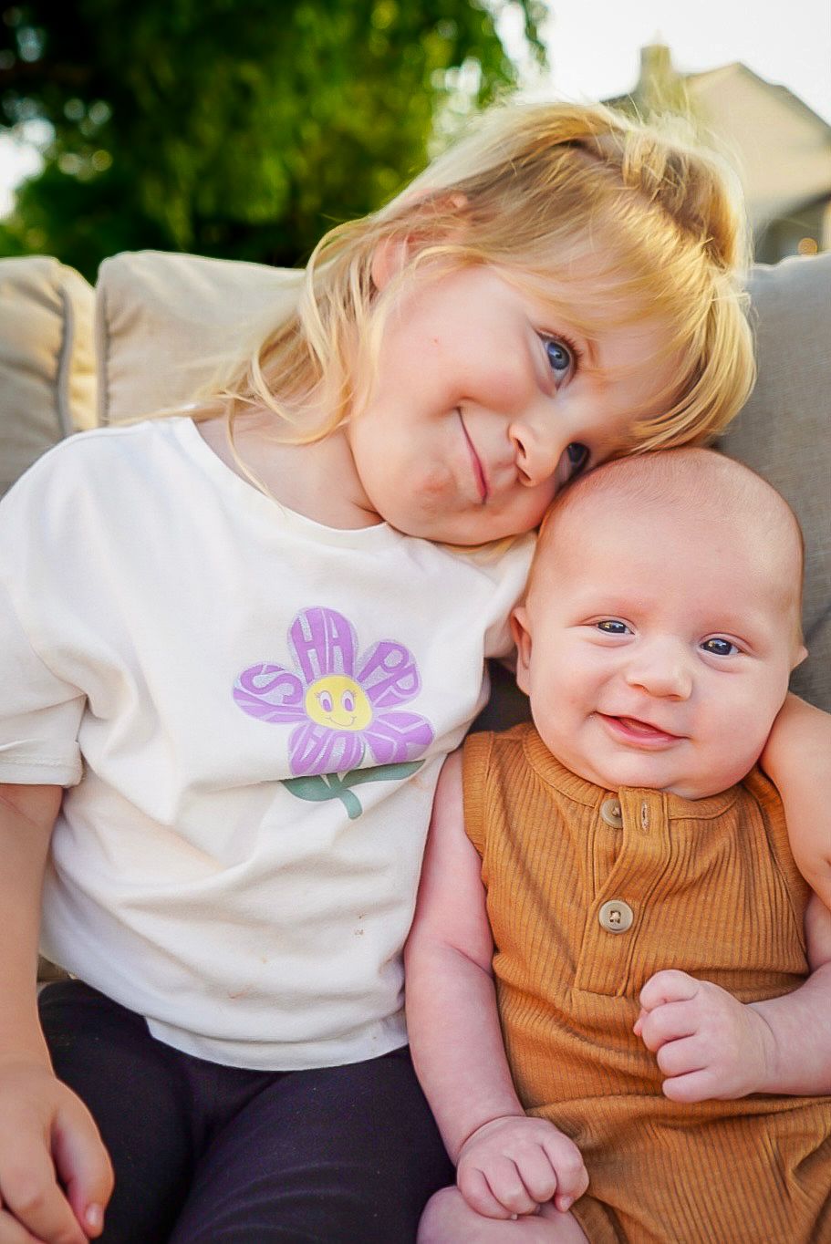Two young children share an affectionate moment while sitting together in outdoor setting.