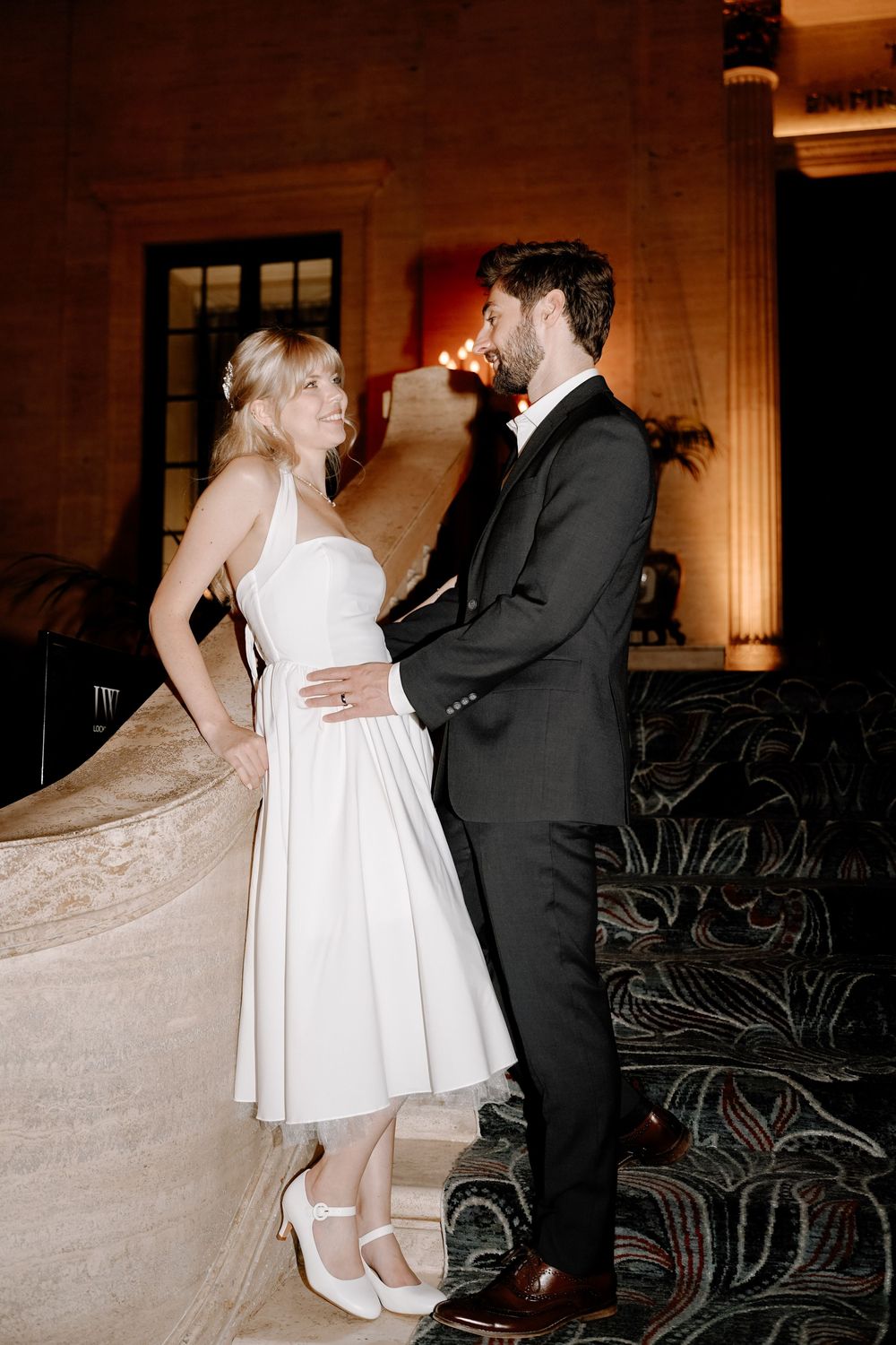 A couple in formal attire dancing together in a dimly lit venue with elegant decor.