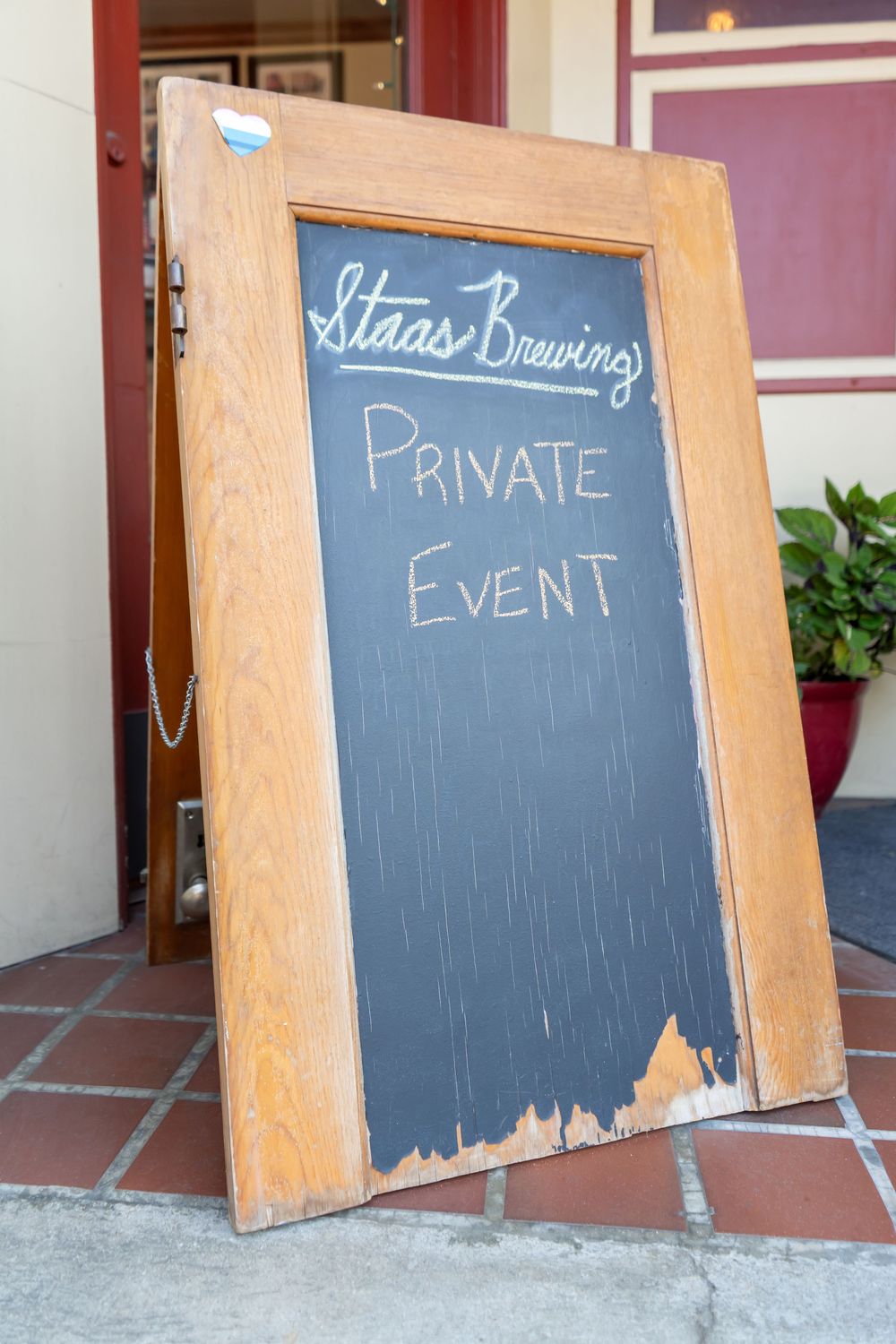 Wooden-framed chalkboard propped against wall with 'Private Event' text written in white chalk against dark surface.