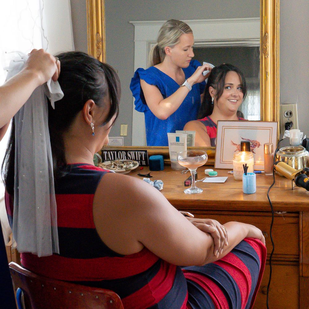 someone getting ready at a vanity mirror in a bedroom.