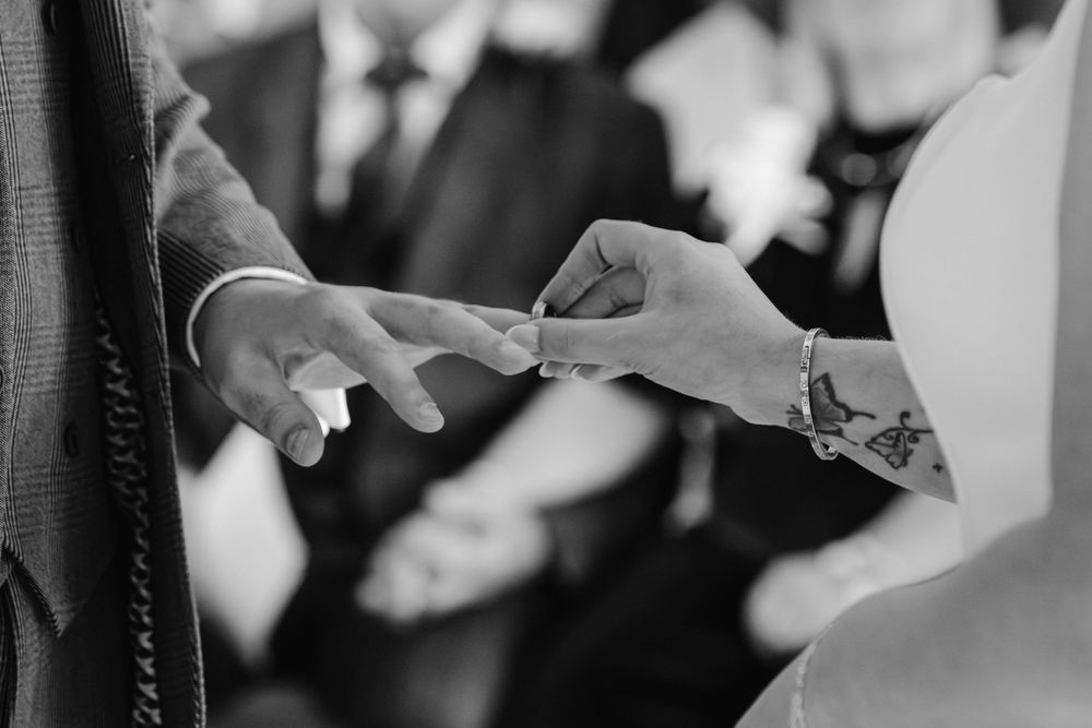 Kingscote Barn Wedding Photographer Zara Davis Photography Cotswolds Gloucestershire Cheltenham close up of bride putting ring on groom
