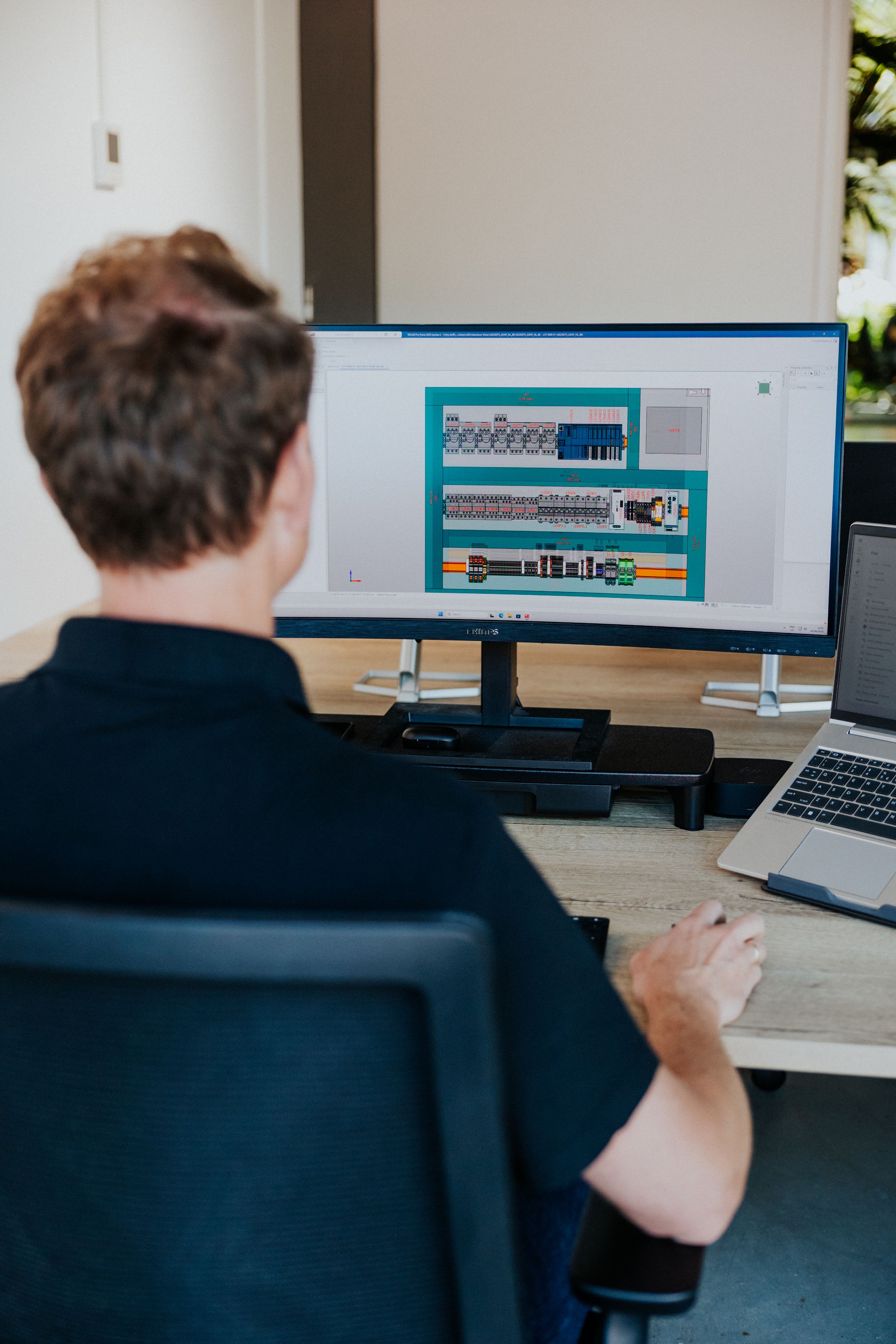 Person working at desk with multiple computer monitors showing technical data.