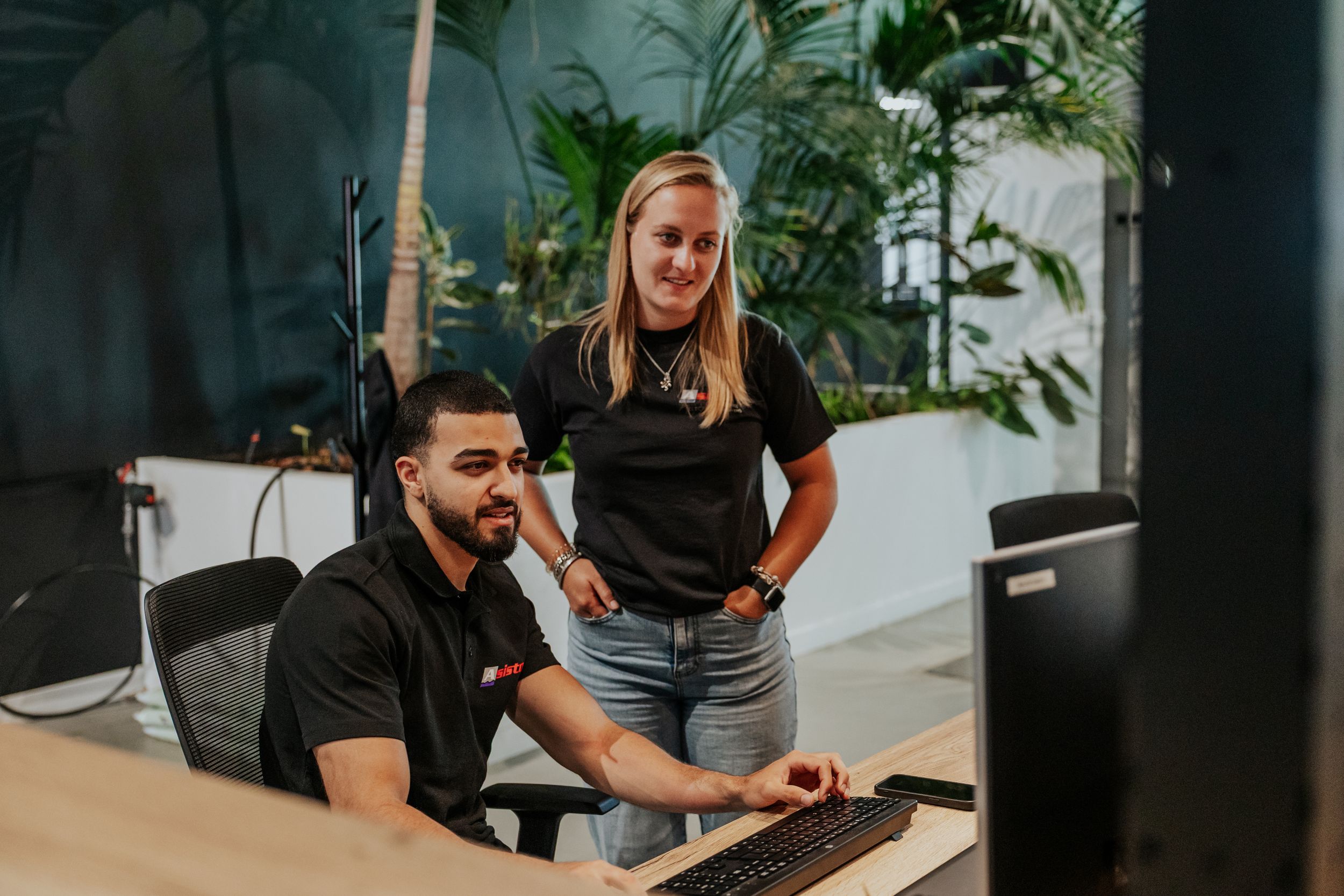 Team members collaborating in modern office space with indoor plants.