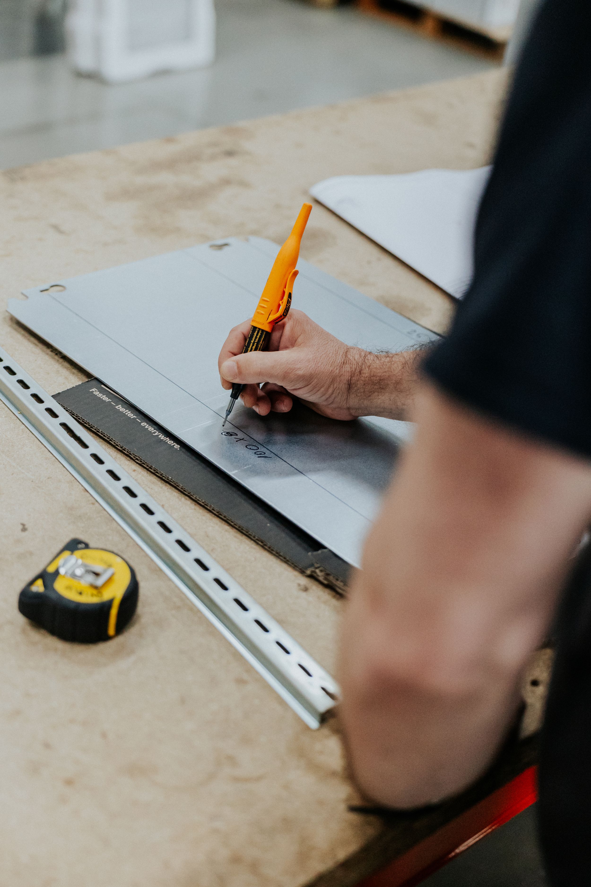Close-up of hands measuring and marking on technical drawing with ruler and pencil.